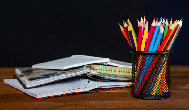 istock Open notebook with pencils in jar in a concept of primary education, design, creativity or art 1345215927
