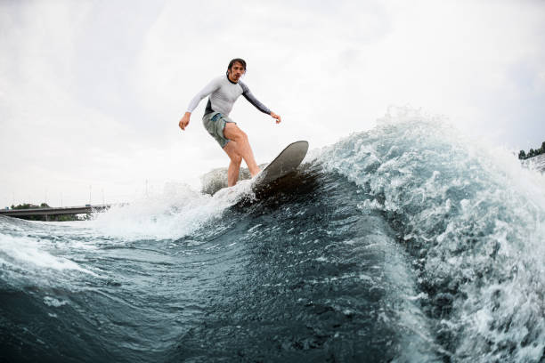 istock Active sportsman skilfully balancing on wave on wakesurf board. 1345216986
