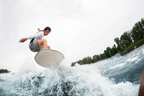 istock young sportsman effectively jumps on wakeboard over splashing wave. 1345218895