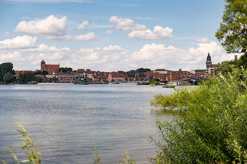 Waren Müritz, the city next to the lake. The harbor side is visible. The towers of the city are in the skyline of the town. Old architecture is in the landscape.