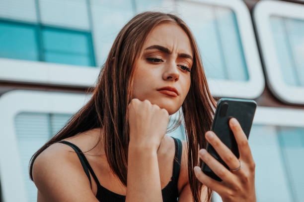 心配した女性はスマートフォンでメッセージをチェック - mobile phone telephone frustration women ストックフォトと画像
