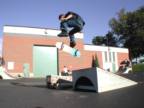 A skateboarder doing a kickflip off of a launch ramp in Lititz, PA.