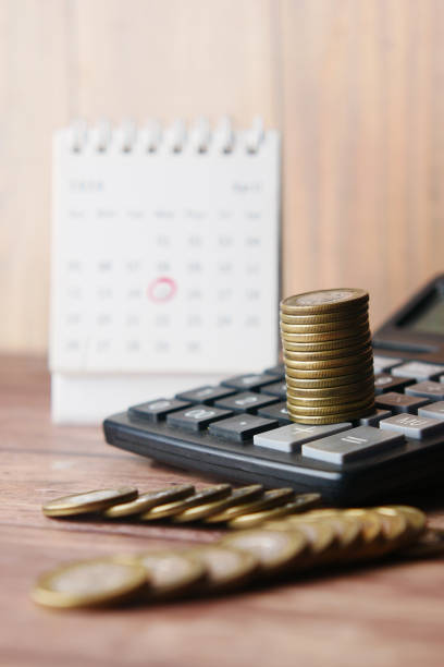 istock stack of coins , calculator and calendar on table 1345235080