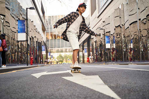 teenage asian child skateboarding outdoors in the street