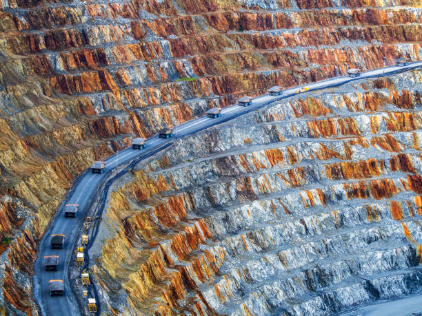 Curve of dump trucks A convoy of dump trucks has made a beautiful line in a mining operations area. copper mine photos stock pictures, royalty-free photos & images
