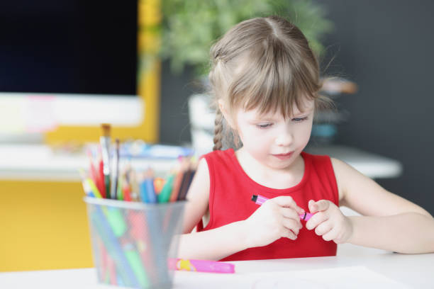 小さな美しい女の子は、自宅のクローズアップで鉛筆を描きます - fine motor skills ストックフォトと画像