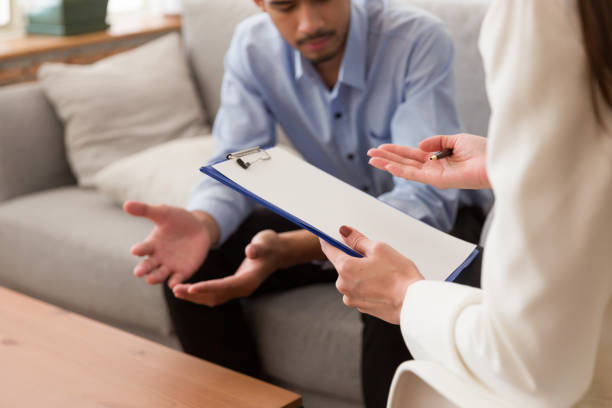 istock Young Asian man talking his problems with professional psychologist while conducting a consultation and making notes to seek advice and therapy 1345246103