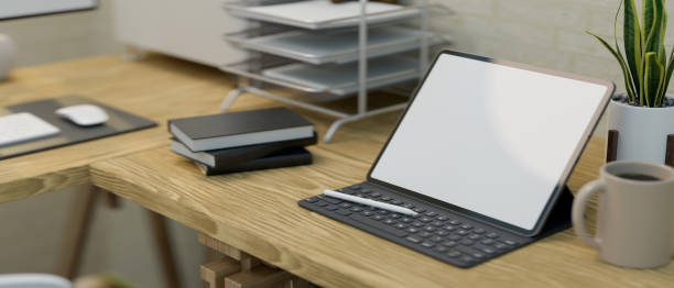 istock Close-up of a modern work station interior design with a portable tablet screen mockup on a wooden table 1345246111