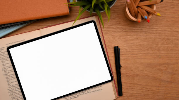 istock Top view of study table with tablet computer blank screen mockup on wooden table 1345246113