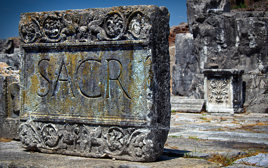 Capua, Campania, Italy - May 12, 2012: A block with 'sacred' written in Latin stands in the ruins of the Santa Maria Capua Vetere Amphitheater, second only in size to the Colosseum of Rome.