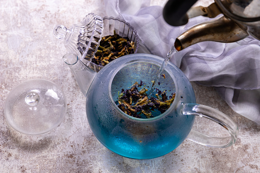 Butterfly pea flower blue tea in a cup with teapot. Healthy detox herbal drink