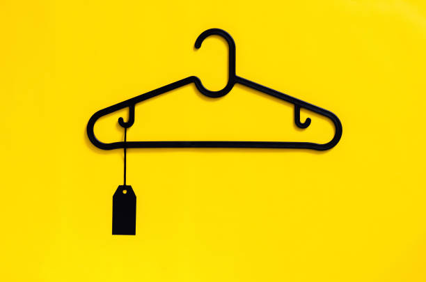 A black hanger with blank black price tag on yellow background. Black Friday concept.