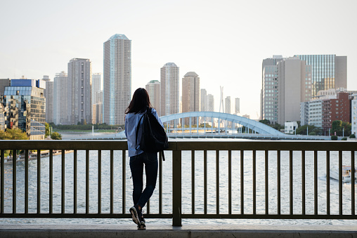 Woman looking at urban skyline from bridge