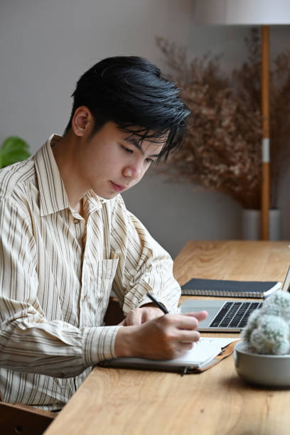 istock Handsome businessman sitting in his office room and making notes on notebook. 1345256805