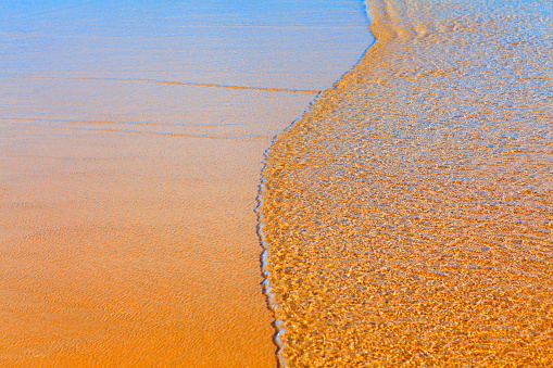 Ocean waves edge on the sand . Transparent water on the sandy beach . Summer coastal background