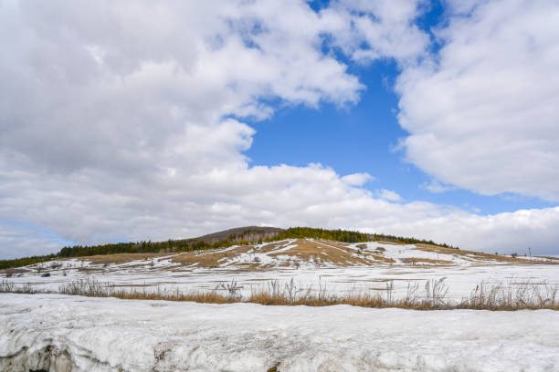 Spring landscape. Snow-covered mountain, forest, beautiful sky and snowdrifts.