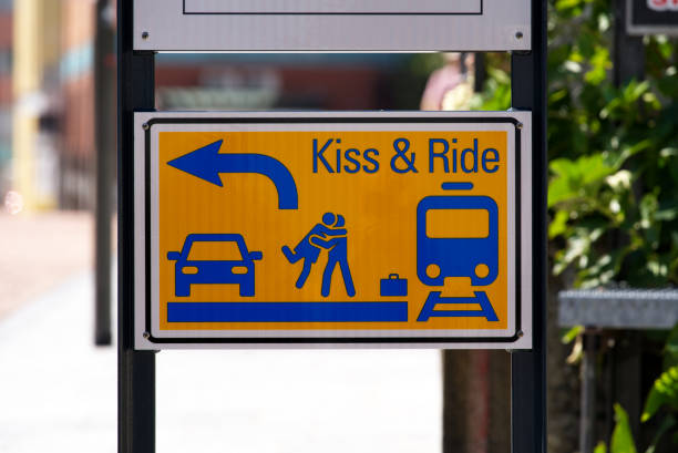 A blue and white road sign indicating the city of Rotterdam, mounted on a grey pole, viewed against a dark, sheltered background
