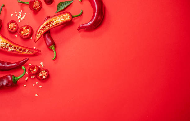 istock Fresh red chilli peppers  and peppers slices isolated on red background. Top view. 1345260764