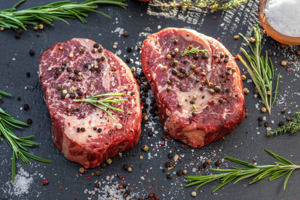 istock Raw Ribeye steaks with salt and herbs on grey board. Top view. 1345260777