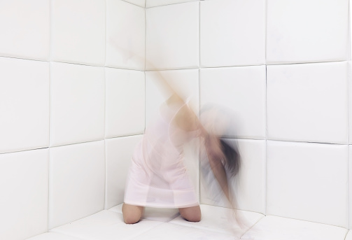 Blur motion photo of a young woman flouncing in a mental hospital padded room