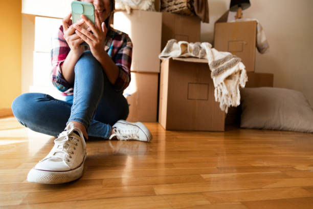istock Young caucasian woman looking cellphone in front of stack of cardboard boxes. Copy space 1345266435
