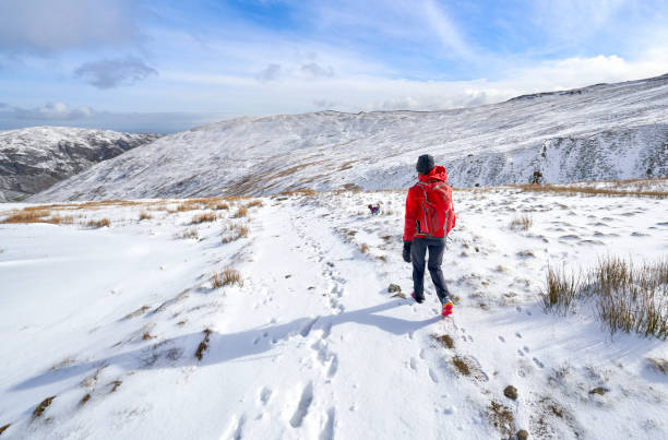 istock A hiker wearing a bright red jacket walking down from a snow covered Catstye Cam towards Glenridding 1345267142