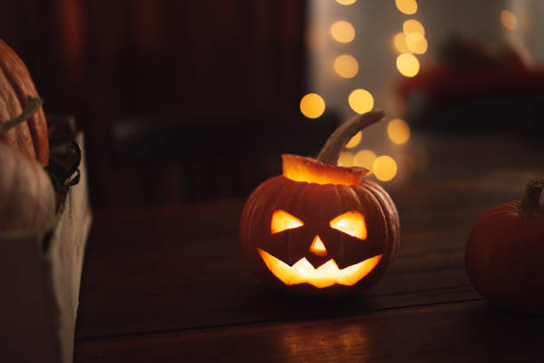 istock Halloween pumpkin with evil face and candles inside on wooden table 1345268686