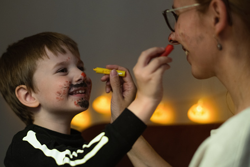 Mother and son painting each other's face  for Halloween celebration