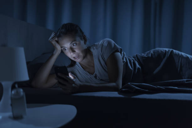 Woman social networking late at night Woman lying in bed and connecting with her phone, she is surprised and shocked horror waking up bed women stock pictures, royalty-free photos & images
