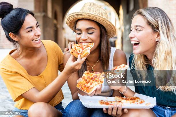 Three Cheerful Multiracial Women Eating Pizza In The Street Happy Millennial Friends Enjoying The Weekend Together While Sightseeing An Italian City Young People Lifestyle Concept Stock Photo - Download Image Now