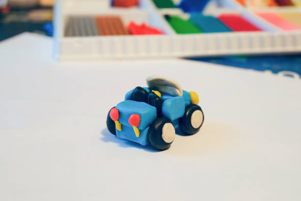 istock Small coupe car made of colored plasticine. Hand-made children's toy on a white surface. Back view. 1345279063