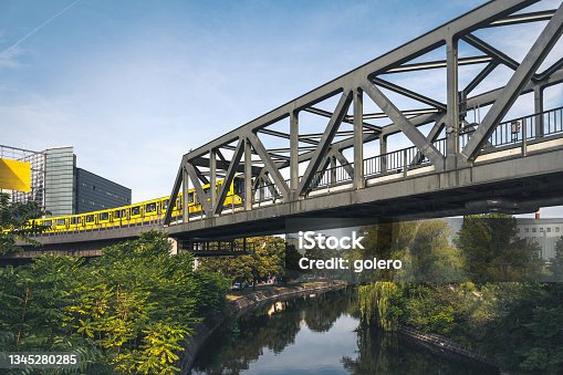 istock yellow metro train on iron bridge passing canal in Berlin Kreuzberg 1345280285