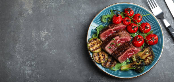 istock Delicious sliced beef steak served on grey table, flat lay with space for text. Banner design 1345281208
