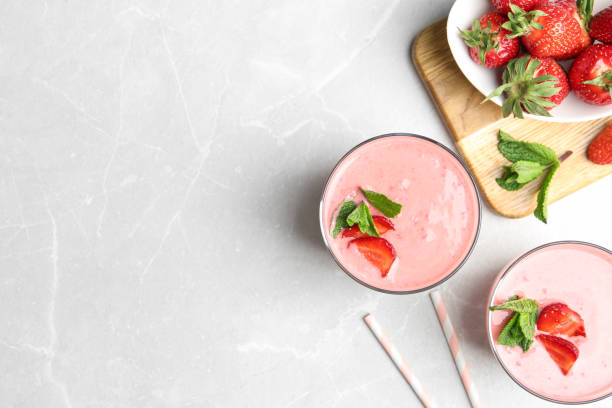 istock Tasty strawberry smoothies with mint in glasses on light grey marble table, flat lay. Space for text 1345282395