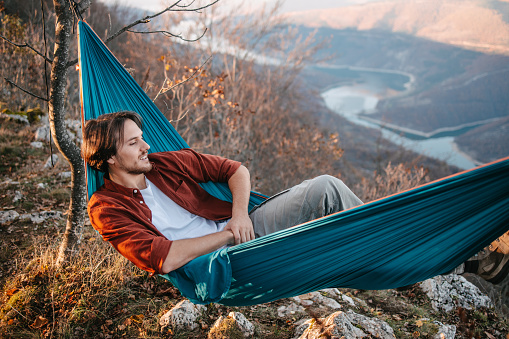 Young adventurist enjoying and relaxing on a hammock. Beautiful mountain scenery