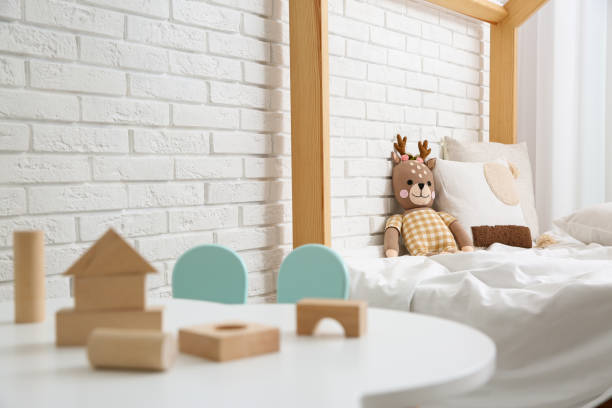 istock Toy deer on bed near white brick wall. Children's room interior design 1345284330