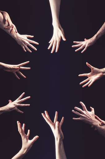Many hands reach out to the center. Vertical orientation. Black background. Copy space. The concept of greed, psychology and social relations.
