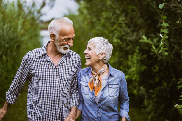 feliz pareja madura comunicándose mientras camina en la naturaleza. - mature adult couple caucasian outdoors fotografías e imágenes de stock