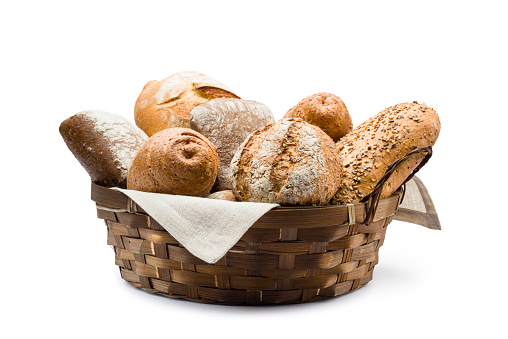 assortment of baked bread in straw basket on white background