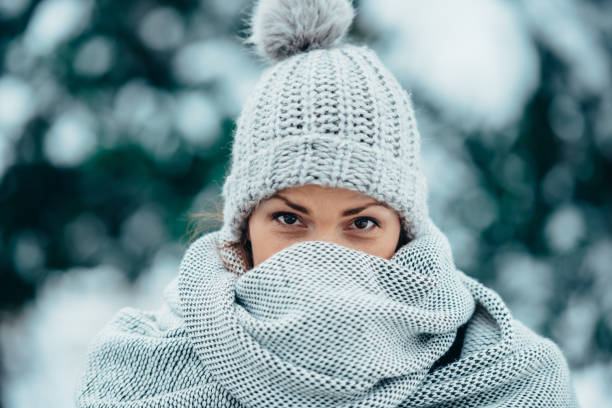 Beautiful young woman wearing scarf and a a hat on a cold winter day Portrait of a beautiful young woman wearing scarf and a a hat on a cold winter day during snow women healthy lifestyle beauty nature stock pictures, royalty-free photos & images
