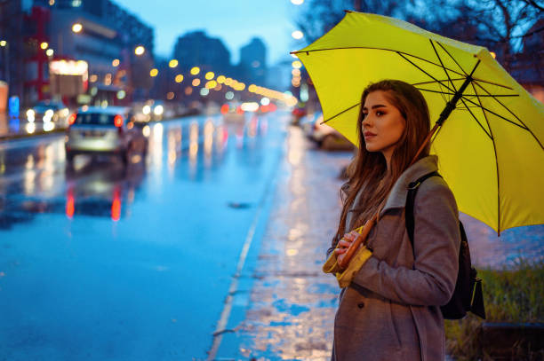 istock Woman holding a yellow umbrella while waiting for a cab 1345287619
