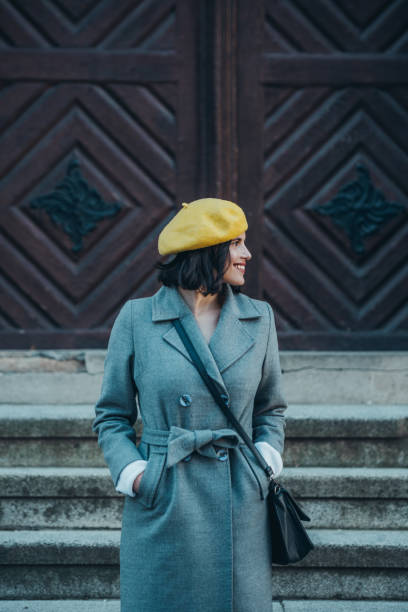 istock Woman using smartphone and wearing yellow beret and a gray coat 1345287648
