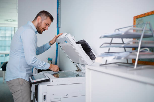 istock Man wiping xerox glass before making copies 1345288429