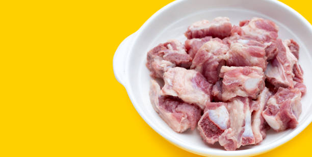 istock Raw pork ribs in white bowl on yellow background. 1345289841