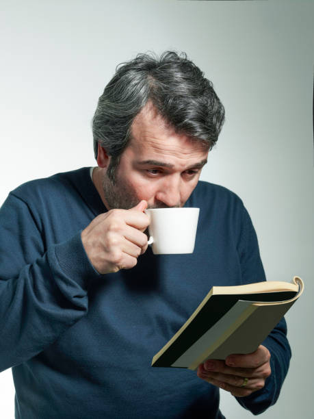 ハンサム�な男はコーヒーを飲んで、本を読む - men sweater excitement satisfaction ストックフォトと画像