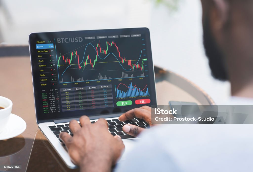 Cropped of black businessman analysing market online on laptop Cropped of black businessman analysing market online while working in office, using website for analysis on laptop, copy space. Business analysis, online trading on stock and markets concept Cryptocurrency Stock Photo