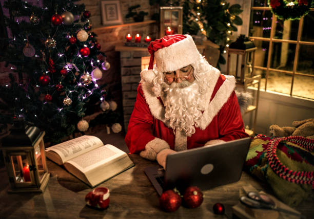 istock happy old Santa Claus using laptop and phone at home 1345292531