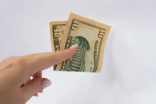 Photo of 10 dollars in the hand close-up on a white isolated background. A ten-dollar bill