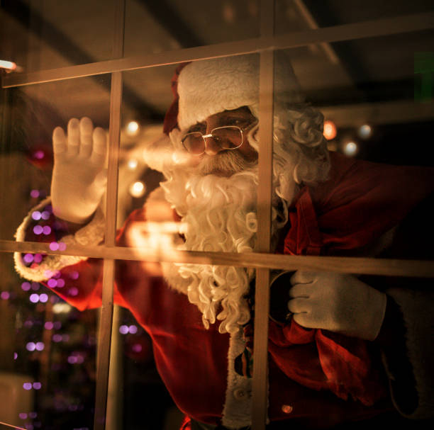 istock happy old Santa Claus using laptop and phone at home 1345293162