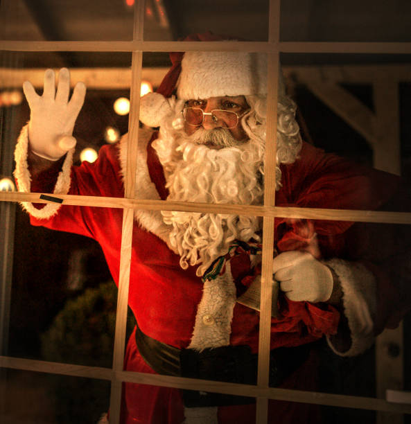 istock happy old Santa Claus using laptop and phone at home 1345293178